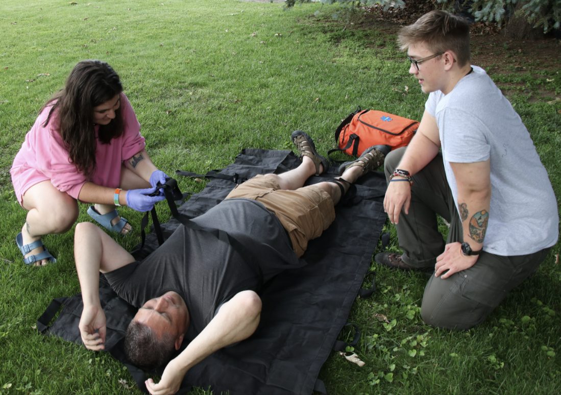 Students practicing patient care on a stretcher outdoors