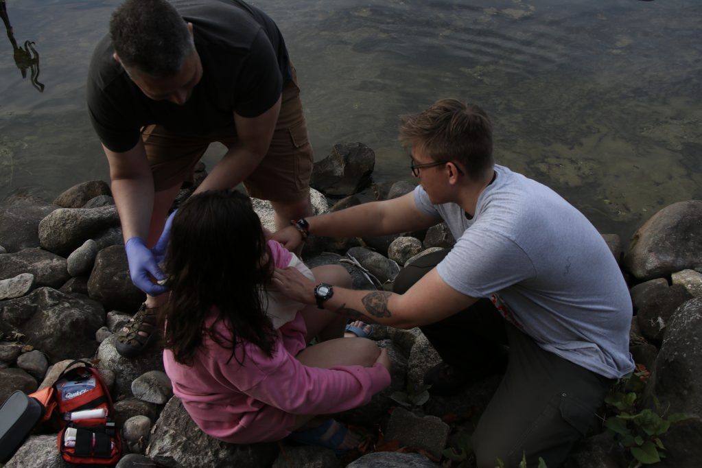 Trailside Training instructors treating a patient on a rocky shoreline
